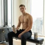 Young athlete mixing BCAA supplements in a shaker bottle for muscle recovery at the gym.